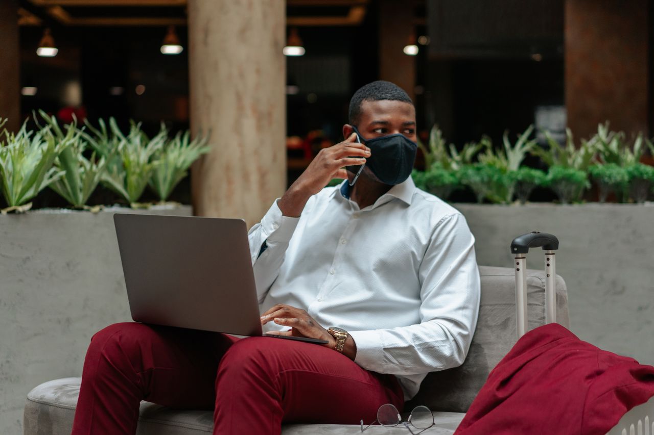 Home Professional man multitasks with laptop and smartphone in a modern indoor sitting area.