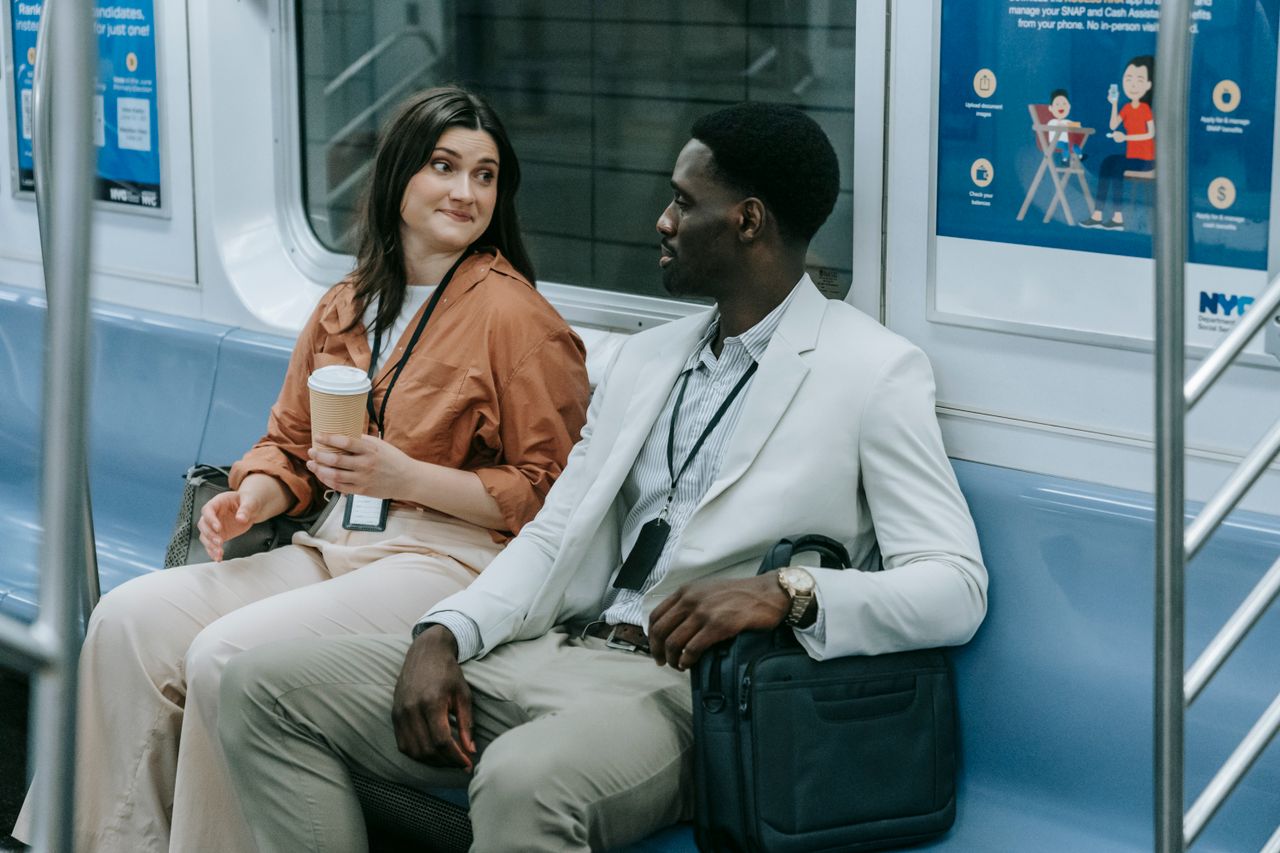 Home Two professionals chatting on a city subway train during their commute.